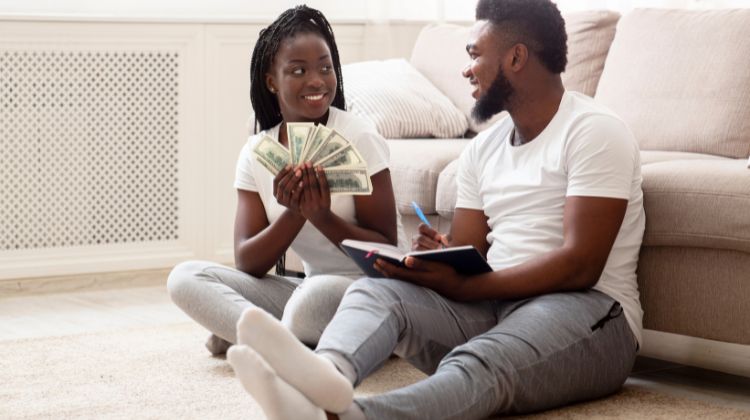 happy couple holding money and taking notes