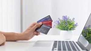 person holding multiple credit cards in front of their computer