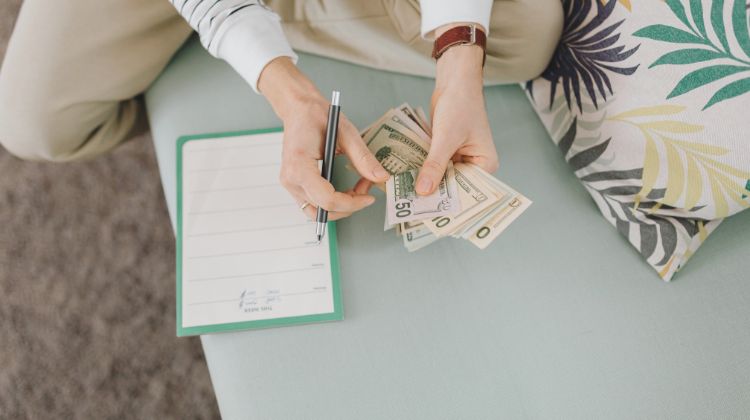 woman counting cash on her sofa with a planner