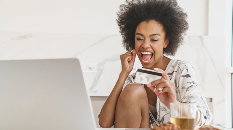 excited woman holding a travel credit card in her hotel room