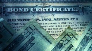 photo of $20 bills on top of an old bond certificate