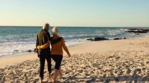older couple walking together on the beach