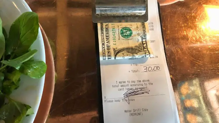 cash tip attached to receipt and clipboard at a restaurant