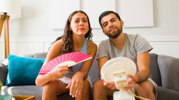 couple sitting with fans in front of their face with no air conditioning