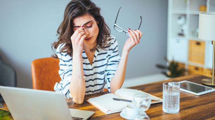 woman sitting at home desk looking stressed